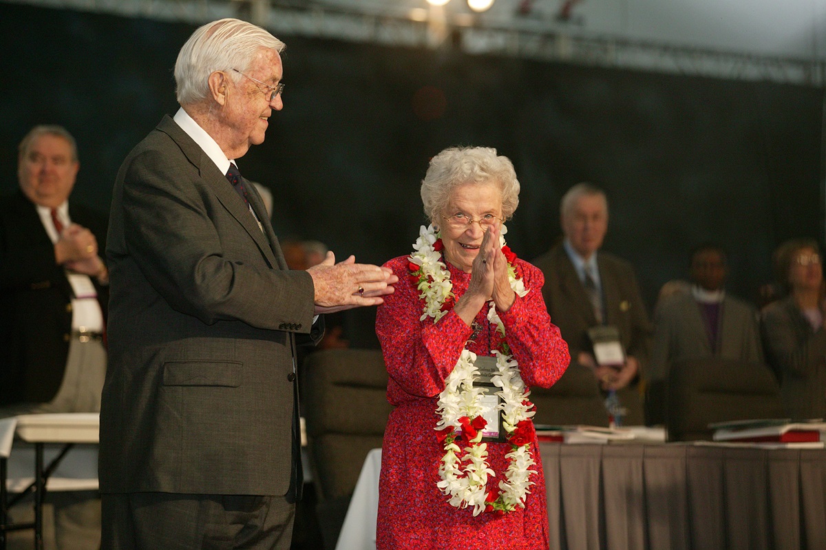 Eunice Mathews acknowledges applause from delegates and guests as the United Methodist Church's 2004 General Conference in Pittsburgh celebrates her lifetime of service to the church. The conference honored Mathews on her 90th birthday. Joining the tribute is her husband, Bishop James K. Mathews. A UMNS photo by Mike DuBose.