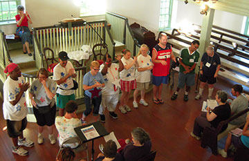 Deaf adults from Camp Pecometh sing during worship at Barratt's Chapel in Frederica, Del. They are encouraged by Bishop Peggy Johnson (rear). A UMNS photo by Barb Duffin.