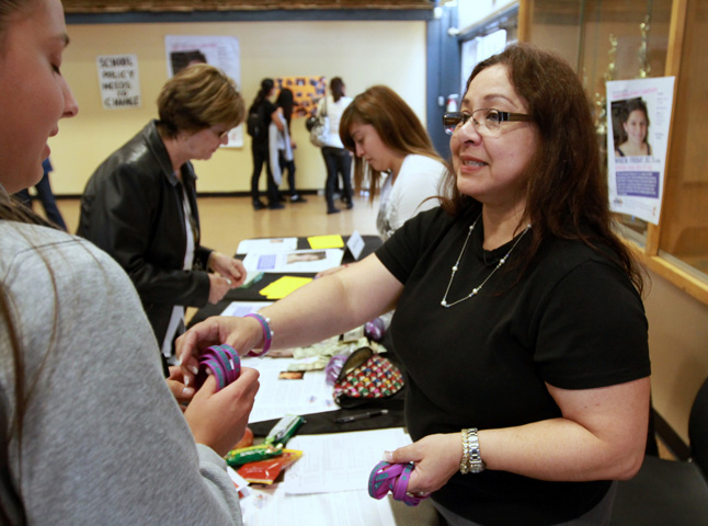 Ann Brownell gives out Amanda Network wrist bands at Andrew Hill High School. 