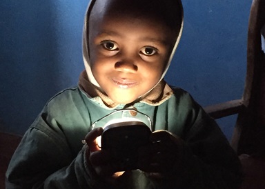 A young boy holds a d.light solar lamp at his home in the Mathare slum, Nairobi, Kenya. Wespath Benefits and Investments has invested about $30 million in solar projects, including d.light. Photo courtesy of d.light