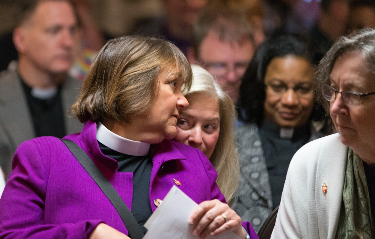 Bishop Karen Oliveto (left) leans over to speak with her wife, Robin Ridenour (behind Oliveto) prior to a meeting of the United Methodist Judicial Council in Newark, N.J. The denomination's top court ruled on April 28 that the consecration of a gay bishop violates church law. At right is Bishop Elaine Stanovsky. Photo by Mike DuBose, UMNS