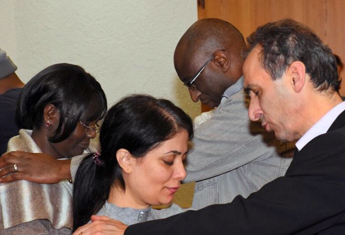 During a seminar on migrant leadership in Germany presented by the General Board of Global Ministries, people from many cultures pray for each other. Photo courtesy of Global Ministries.