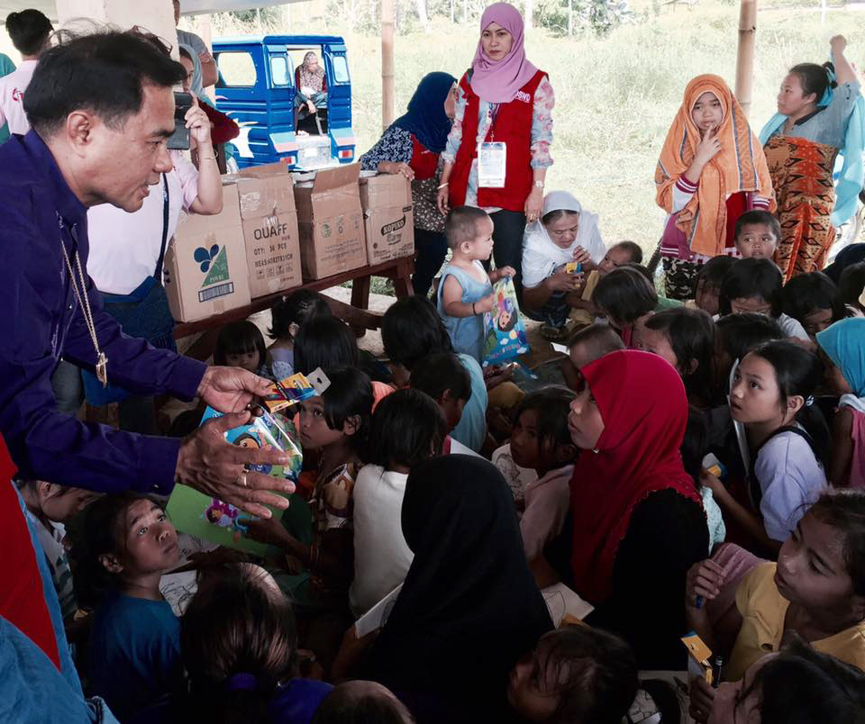 Bishop Rodolfo A. Juan (left) hands out crayons to children who fled with their families to escape fighting between government forces and Islamic State militants on the island of Mindanao in the Philippines. The families are staying at an evacuation center in Bito-Buadi, Marawi City, where United Methodists are helping those displaced. Photo by the Rev. Israel M Painit
