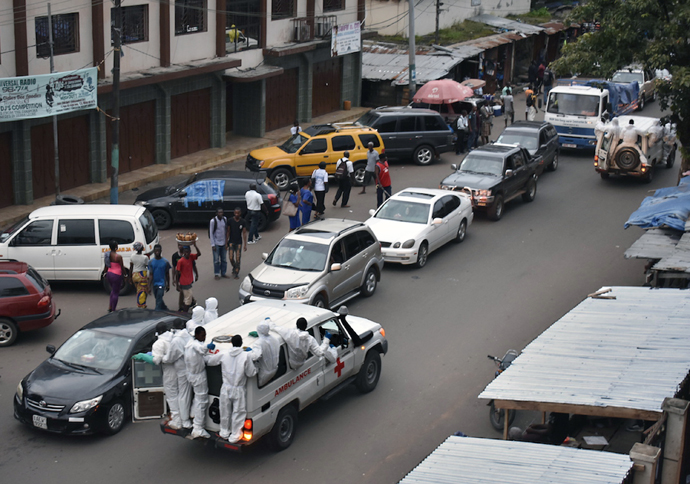 An ambulance with emergency personnel hanging on to the outside drives through a busy street in Freetown, Sierra Leone, after a mudslide devastated the Sugar Loaf Mountain Regent area. Photo by Phileas Jusu, UMNS.   