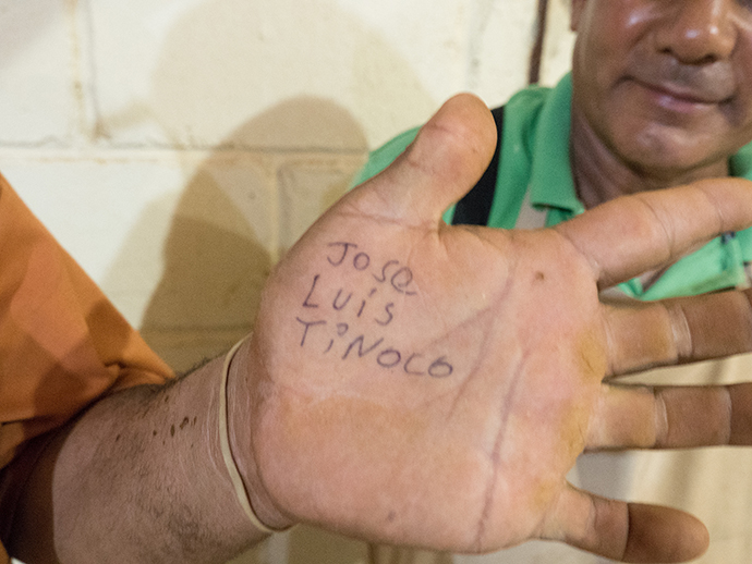 It is loud inside the cigar factory, Jose Luis Tinoco found it easier to write his name on his hand for the visiting reporter. Tinoco and Santos Martinez work in the fermentation process, they rehydrate each leaf using a rubber hose in a small humid cinder-block room. Photo by Kathy L. Gilbert, UMNS.