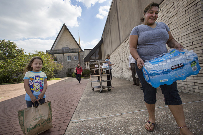Four-year-old Joely Salguero and Marty Pineda carry supplies distributed by Houston’s Westbury United Methodsit Church to flood victims of Hurricane Harvey. Photo by Kathleen Barry, UMNS.