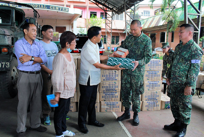 Bishop Rodolfo A. Juan (third from right), along with other clergy and lay people, distributes water and medicine to Marines. Photo courtesy of the Rev. Capt. Eduardo Copliting.
