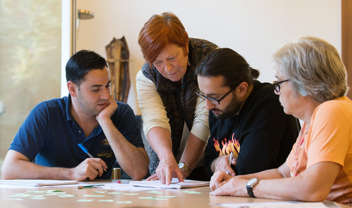 Uta Dauner Eisbrenner helps Muhammad Mshehadat (left) and Maker Araksousi with a vocabulary exercise during a German class for recent immigrants at the United Methodist Church of the Caller in Frankfurt, Germany. Helping, at right is volunteer Christa Shweitzer.  Photo by Mike DuBose, UMNS.