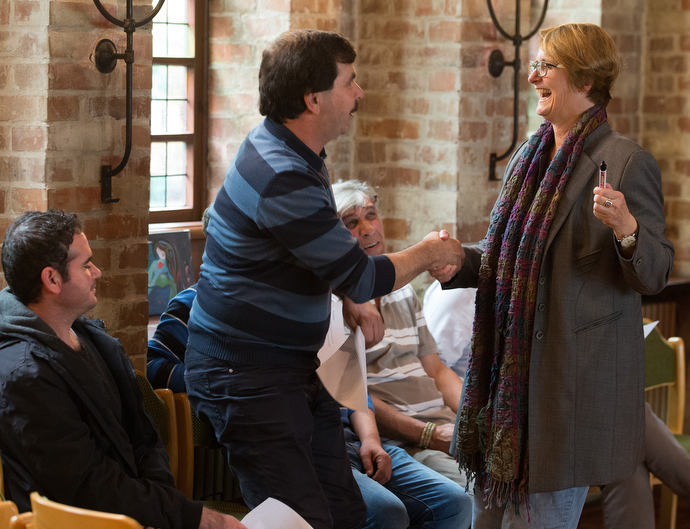 The Rev. Susanne Nießner-Brose (right) greets Aziz, a recent immigrant from Syria, during a German class she is leading at the United Methodist Church of the Redeemer in Bremen, Germany. Photo by Mike DuBose, UMNS.