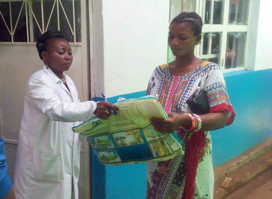 Anny Butunga Mwindulwa distributes a mosquito net to new mother Aziza Rachel outside the Irambo Clinic maternity ward in Bukavu, Democratic Republic of Congo. Photo by Philippe Kituka Lononga, UMNS.