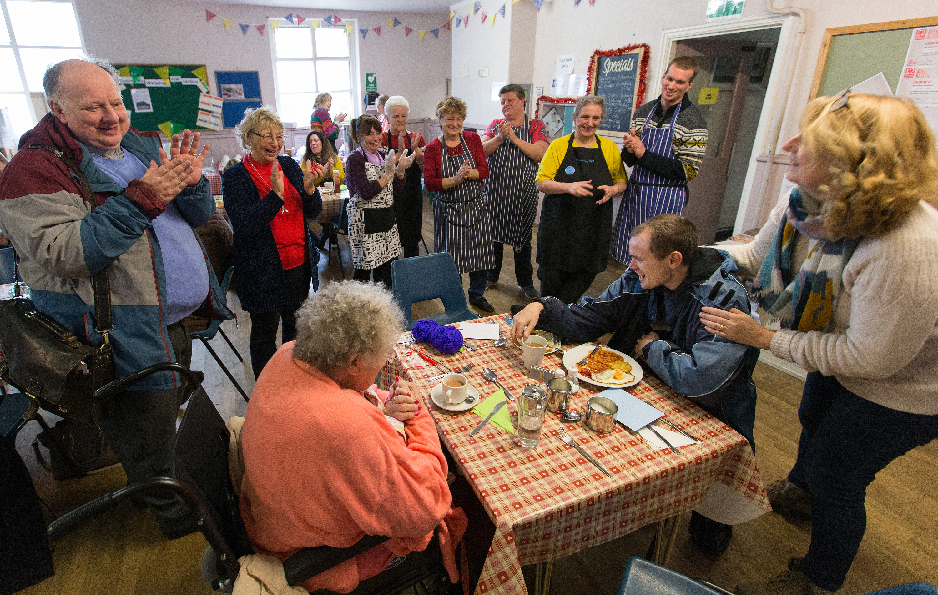 Community members, staff and volunteers wish Craig Kirwin (seated, right) a happy birthday during the twice-weekly community café at Wharton and Cleggs Lane Church and Community Centre in Little Hulton, England. Photo by Mike DuBose, UMNS.