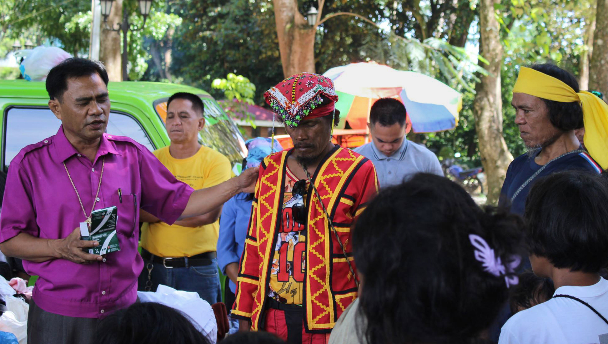 Bishop Rodolfo A. Juan (left) prays for a leader (red vest) at a camp for displaced people in Malaybalay, Philippines, in 2017. On Feb. 22, Juan made contacts on behalf of a team of five — including two missionaries with the United Methodist Board of Global Ministries— who were briefly detained at a police checkpoint in Koronadal City, Philippines. File photo courtesy of Dan Ela.