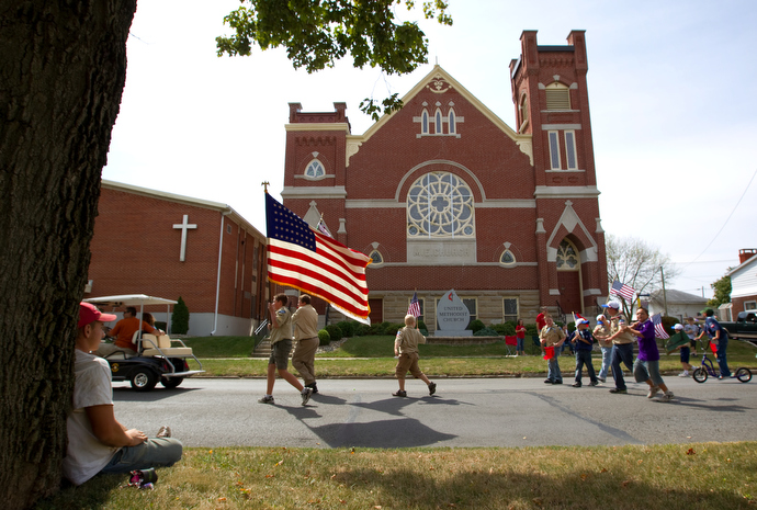 Boy Scouts from Troop 222 march in front of Leipsic (Ohio) United Methodist Church in 2010 during the parade that kicks off the town's annual Fall Festival. Watching the parade, at left, is Luke Lammers. File photo by Mike DuBose, UMNS.