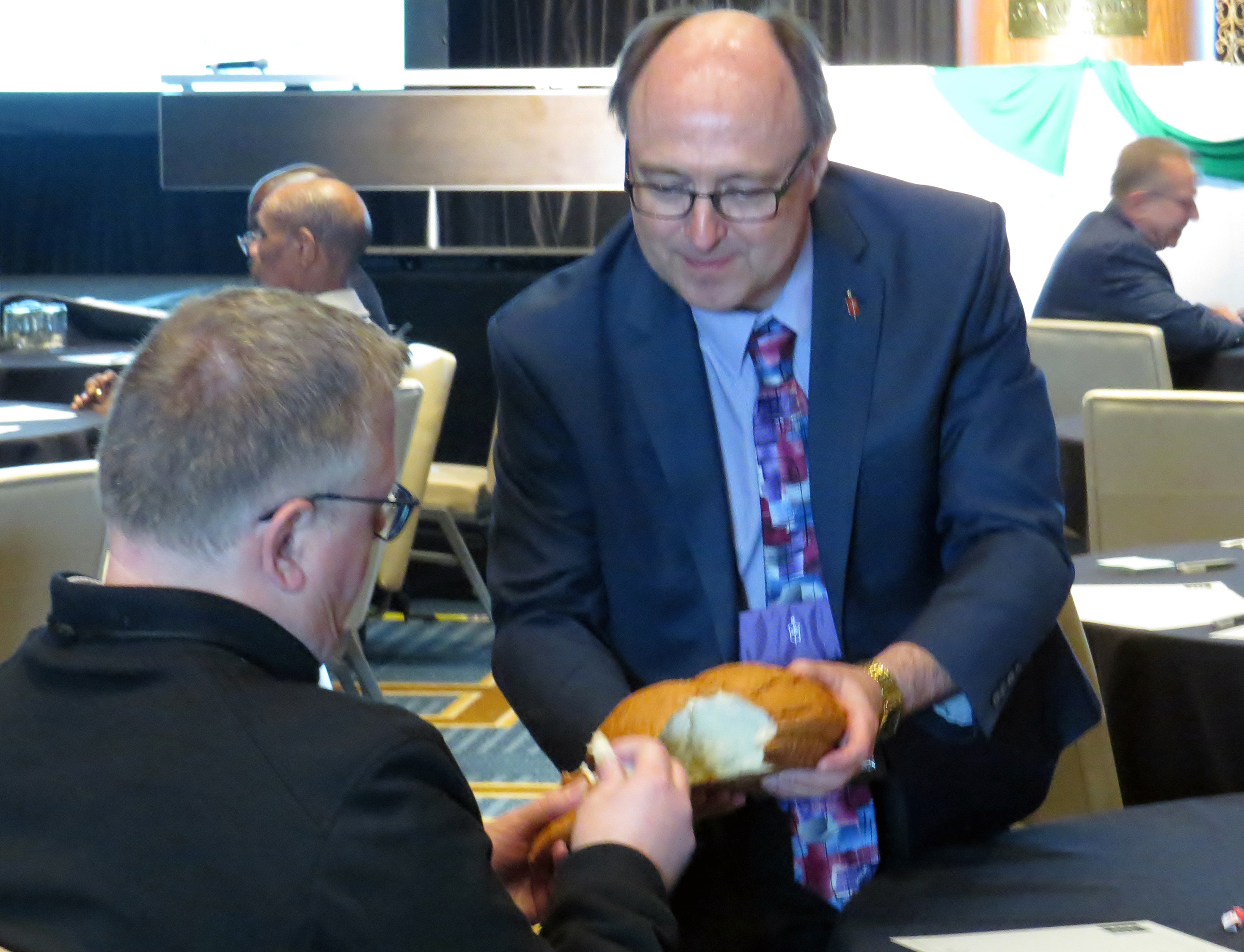 Michigan Area Bishop David Bard serves communion bread to Nordic-Baltic Area Bishop Christian Alsted during closing worship at the meeting of the Council of Bishops. Photo by Sam Hodges, UMNS.