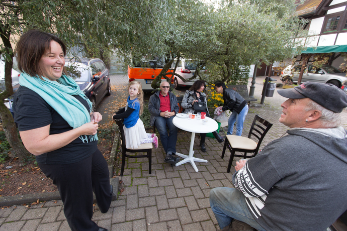 The Rev. Heike Miller (left) visits with Harry Faust (right) and other community members outside the United Methodist Church in Lorsbach during Café Gegenüber, a weekly gathering for coffee, cake and coversation. The café helps the church serve as a social center in the community. Photo by Mike DuBose, UMNS.