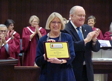 Kay Schecht, standing with Bishop Mike McKee, accepts the Foundation for Evangelism’s Distinguished Evangelist Award during the April 8 worship service at Plymouth Park United Methodist Church, in Irving, Texas. Photo by Bill Fentum.