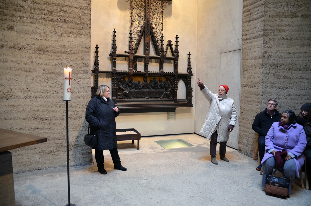 In the Chapel of Reconciliation at the Berlin Wall Memorial, tour guide Christiane Schmidt (right) explains to those gathered how the altarpiece from the original Church of Reconciliation was damaged when the building was blown up by the East German government in 1985. The piece survived the demolition and now hangs in the new chapel. Bishop Rosemarie Wenner of Germany (left) looks on. Photo by Klaus U. Ruof, UMNS.