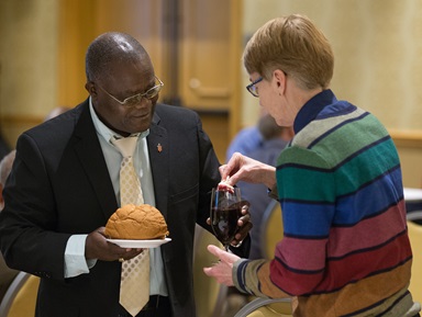Bishop José Quipungo of the East Angola Area (left) and Sue Laurie of Love Prevails, an unofficial group that advocates for equality of LGBTQ individuals, share Holy Communion during the United Methodist Council of Bishops meeting in Chicago. Photo by Mike DuBose, UMNS.