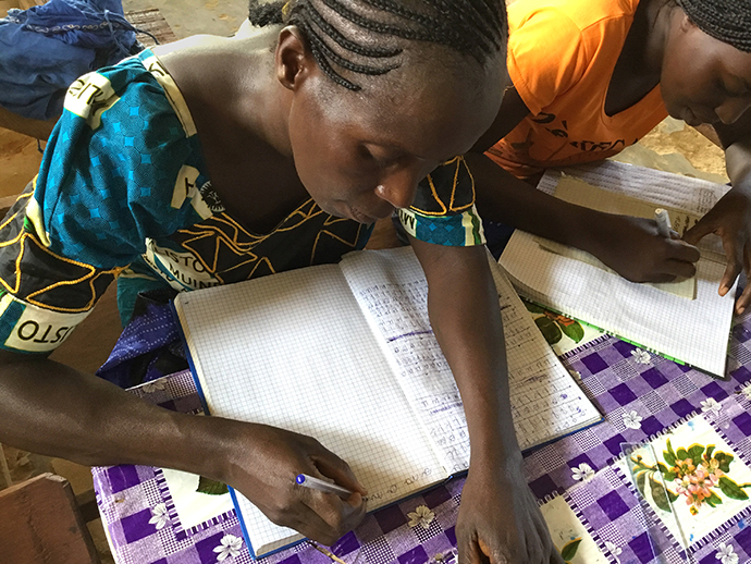 Two women write in notebooks during training provided for the wives of theology students at Kindu United Methodist University in Democratic Republic of Congo. Photo by Judith Osongo Yanga, UMNS.