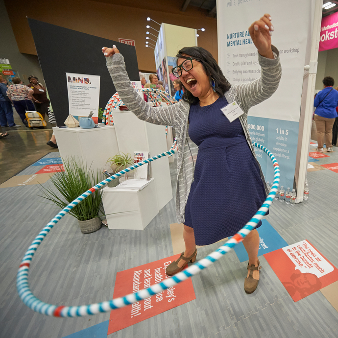 The Rev. Shalom Agtarap uses a Hula-Hoop at a health exhibit in the exhibit hall of the assembly. Photo by Paul Jeffrey for United Methodist Women.