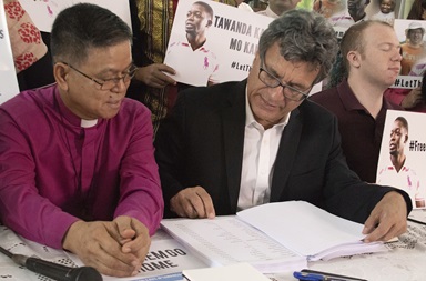 Thomas Kemper (center), top executive of the United Methodist Board of Global Ministries, shows Philippine Bishop Ciriaco Q. Francisco a list of people calling for the release of two missionaries during a press conference at Good Samaritan United Methodist Church in Manila, Philippines, July 2. Photo by Jan Snider, UMCom.
