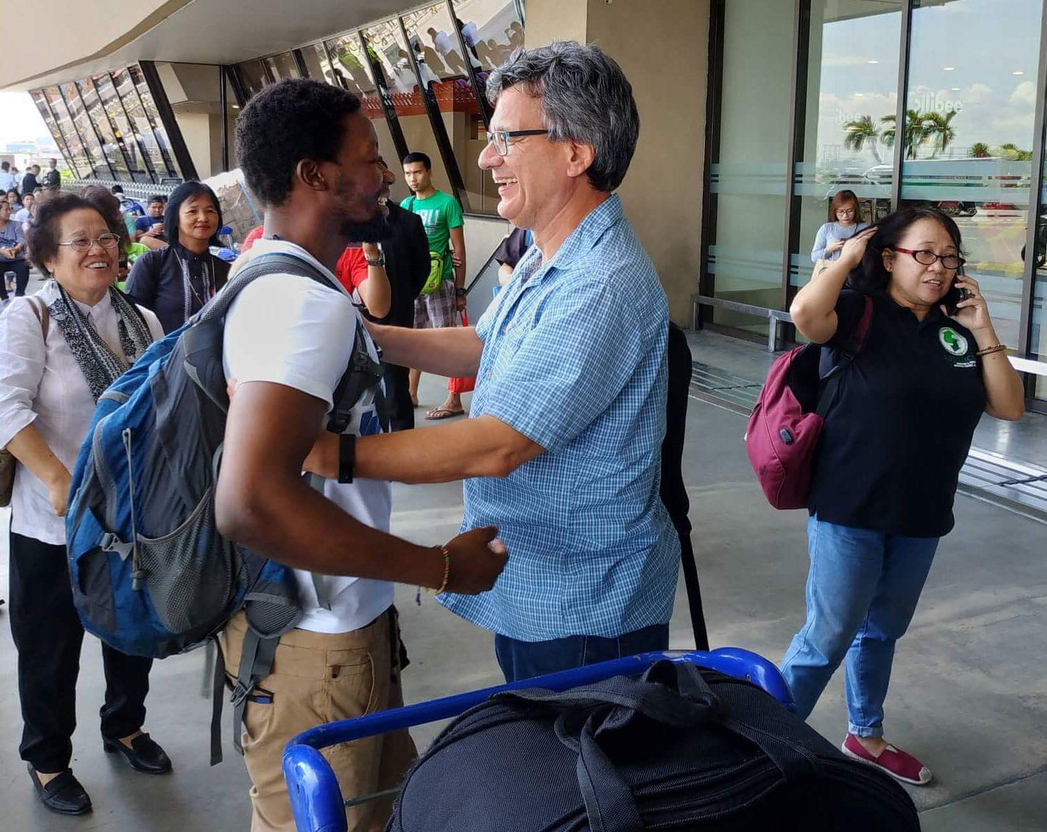 United Methodist missionary Tawanda Chandiwana (left foreground) is embraced by Thomas Kemper, head of the denomination’s Board of Global Ministries, at the Ninoy Aquino International Airport in Manila, Philippines, after Chandiwana was released from a detention center and allowed to leave the country. Photo by Mendoza Adrian.