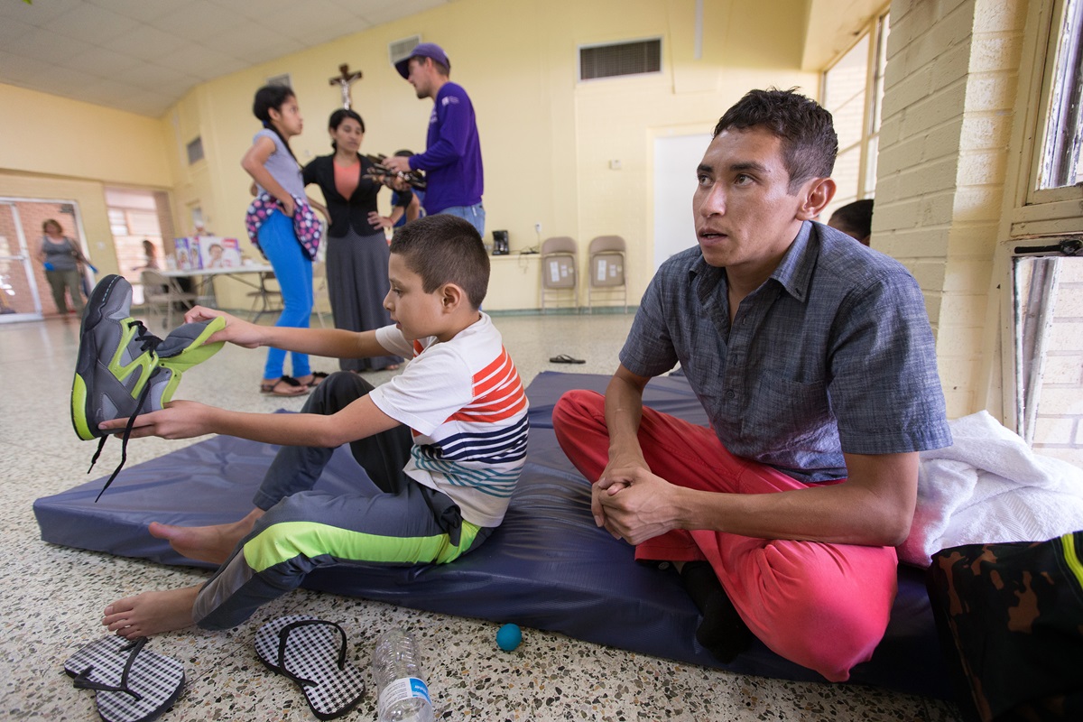 Oliver (derecha) y Anthony su hijo de 8 años descansan en un refugio desbordado de inmigrantes recientes, en la Basílica de Nuestra Señora de San Juan del Valle en McAllen, Tejas. Ellos huyeron de su Honduras natal por miedo a la violencia de las pandillas, y pidieron que sus nombres reales no se usen.