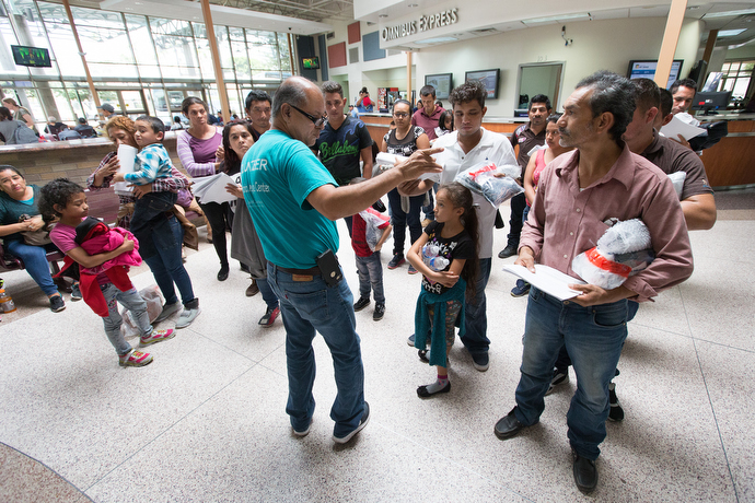 Eli Fernandez (center) helps direct immigrants inside the bus station in McAllen. Photo by Mike DuBose, UMNS.