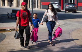 Catholic Charities volunteer Maria Peña (right) leads Honduran immigrants Isaác Rivera Ramos and his daughter Katerin to the bus station in McAllen, Texas. Photo by Mike DuBose, UMNS.