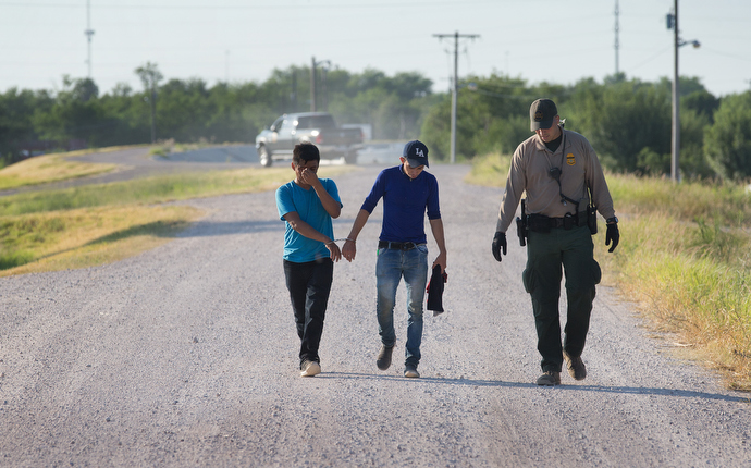 A U.S. Border Patrol agent escorts two young men who were caught entering the U.S. illegally. Photo by Mike DuBose, UMNS.