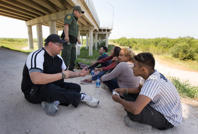 The Rev. Robert Lopez (left) visits with a group from El Salvador and Guatemala who were caught entering the U.S. illegally by crossing the Rio Grande near McAllen. Lopez, superintendent of The United Methodist Church's El Valle and Coastal Bend Districts in the Rio Texas Conference, said the group had been traveling for a month to reach the U.S. Photo by Mike DuBose, UMNS.
