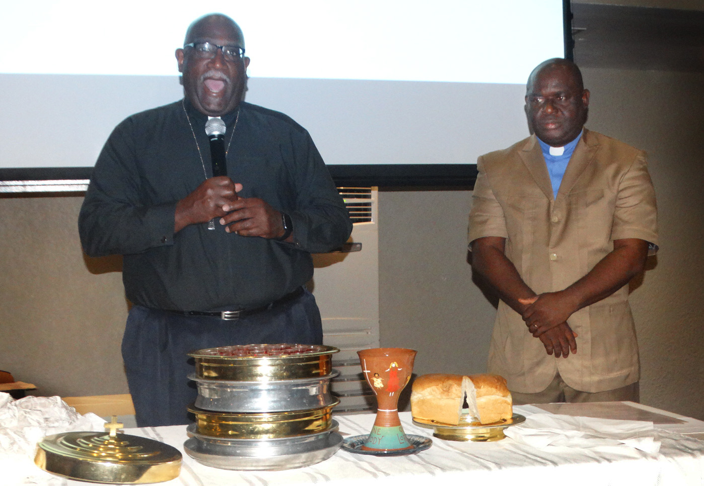 Bishop Gregory V. Palmer (left) of the Ohio West Area and the Rev. James Boye-Caulker of Sierra Leone bless the elements of Holy Communion during closing worship for the Africa Comprehensive Plan meeting in Freetown, Sierra Leone. Photo by Phileas Jusu, UMNS.