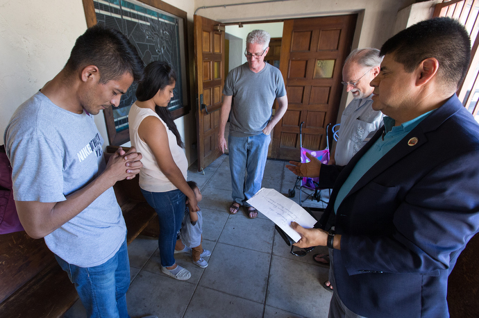 The Rev. Joel Hortiales (right), a United Methodist missionary with the Board of Global Ministries, leads a prayer with Jose Antonio Marchas Novela (left), his wife, Irlanda Lizbeth Jimenez Rodriguez, and their 1-year-old son, Jose Antonio, at the Christ United Methodist Ministry Center. Joining the prayer are the Revs. John Fanestil (center) and David Farley. Photo by Mike DuBose, UMNS.