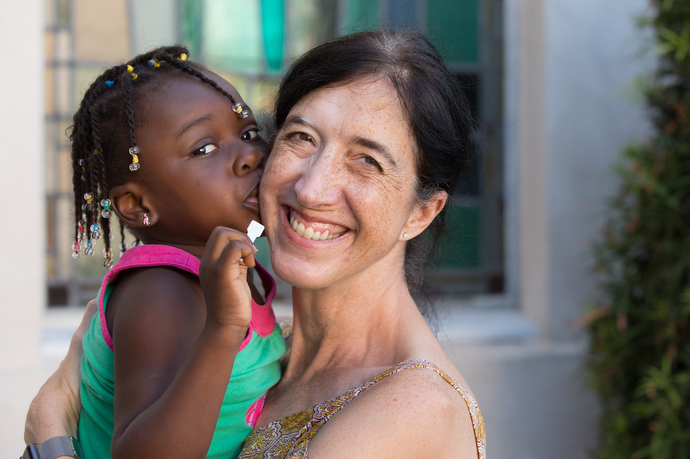 Volunteer Kathryn LaPointe gets a kiss from Haley, 4, a recent immigrant from Benin in West Africa, who is staying at Christ United Methodist Ministry Center. Photo by Mike DuBose, UMNS.