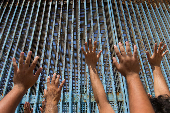 Parishioners of the Border Church in Tijuana, Mexico, raise their arms skyward beneath the border fence at El Faro Park in Tijuana. The Methodist Church of Mexico and The United Methodist Church in the U.S. share communion each Sunday across the border. Photo by Mike DuBose, UMNS.