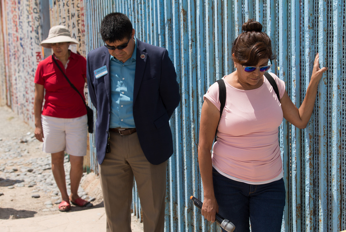 Yolanda Varona Palacios (front) joins in prayer at the border wall that separates Mexico from the U.S. at El Faro Park in Tijuana. Palacios started Dreamers Moms when she was deported in 2014. Behind her is the Rev. Joel Hortiales. Photo by Mike DuBose, UMNS.