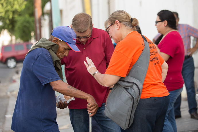 The Rev. Jacob Van Der Schaaf (center) and Elly Rodiles (right) from La Santísima Trinidad Methodist Church offers breakfast and a prayer to Jesus Perez in Mexicali. Photo by Mike DuBose, UMNS.