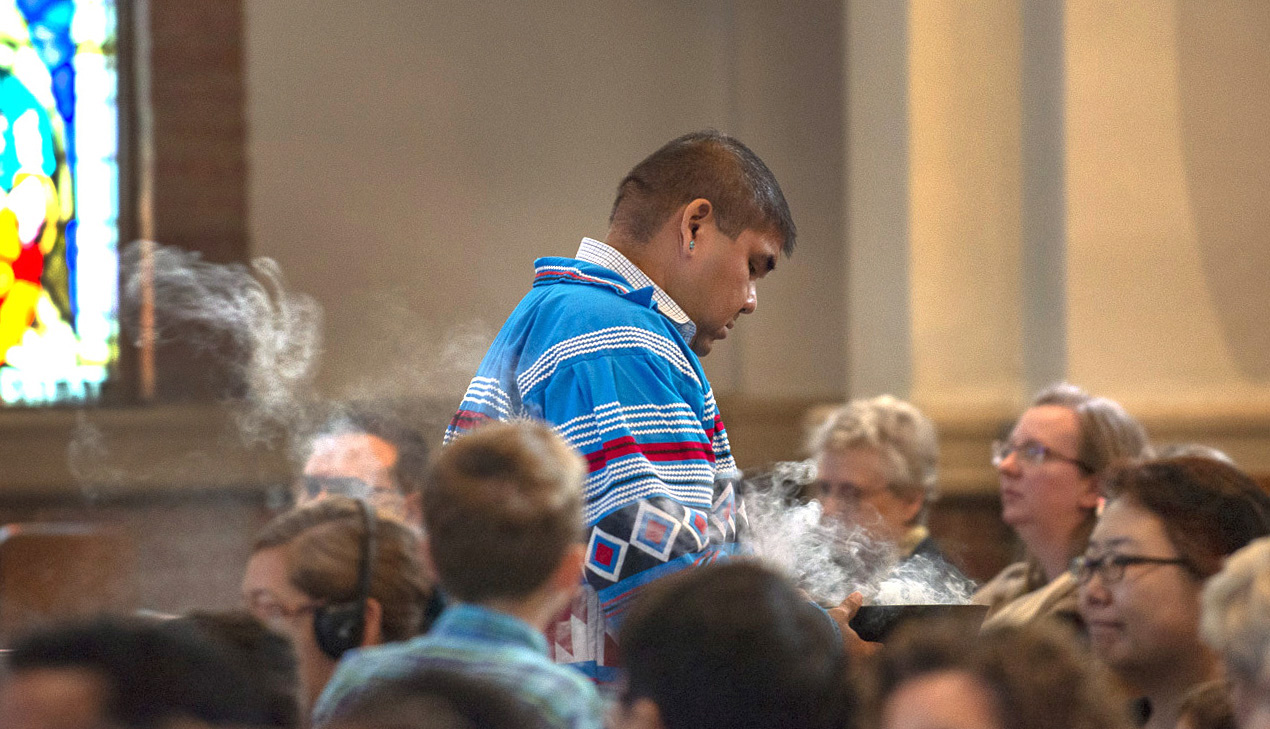 The Rev. Chebon Kernell walks through the sanctuary at Grace United Methodist Church in Atlanta offering incense during the closing worship service for Global Ministries.  Photo by Hector Amador. 
