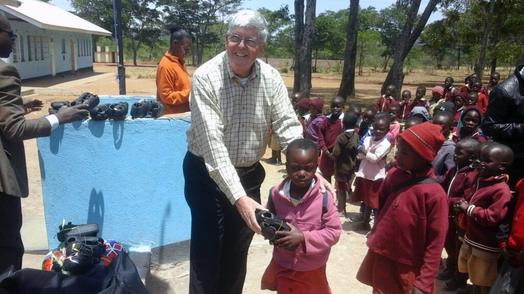 Charlie Moore, a member of Community United Methodist Church in Crofton, Maryland, and team leader of the Zimbabwe Volunteers in Mission, hands shoes to a student at Hanwa Mission School in Zimbabwe. For over 20 years, the U.S. church has been working with United Methodists in the Zimbabwe West Conference to improve lives in the rural Murewa District. Photo by Chenayi Kumuterera, UMNS.