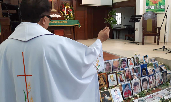 The Rev. Nonie Aviso of the United Church of Christ in the Philippines blesses photos of the victims of drug-related violence during a service at St. Paul United Methodist Church in Manila. Photo courtesy of Juliet Solis.