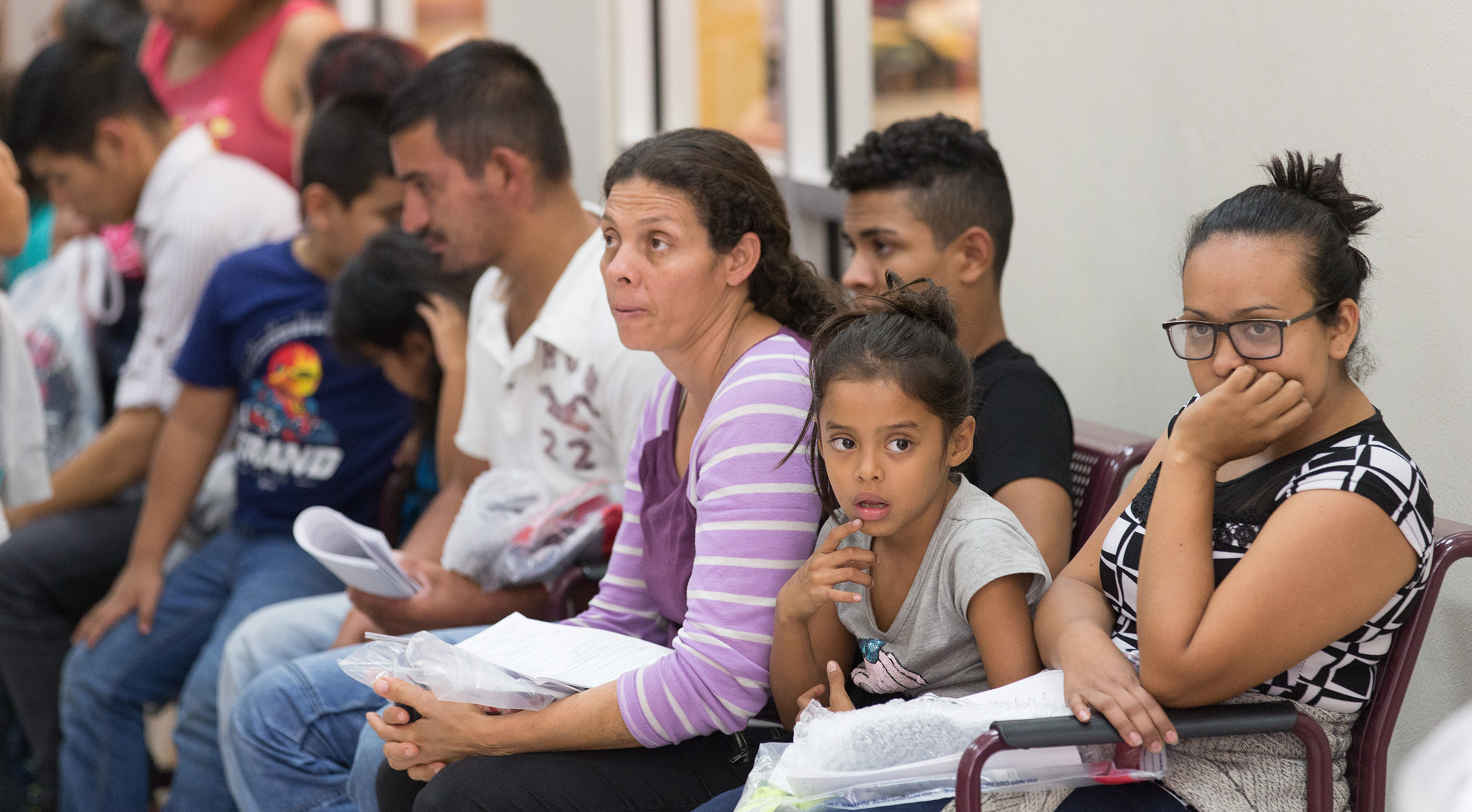 Immigrants who have just been released from a U.S. Border Patrol detention facility wait at the bus station in McAllen, Texas, in this photo from Aug. 1. Photo by Mike DuBose, UMNS.