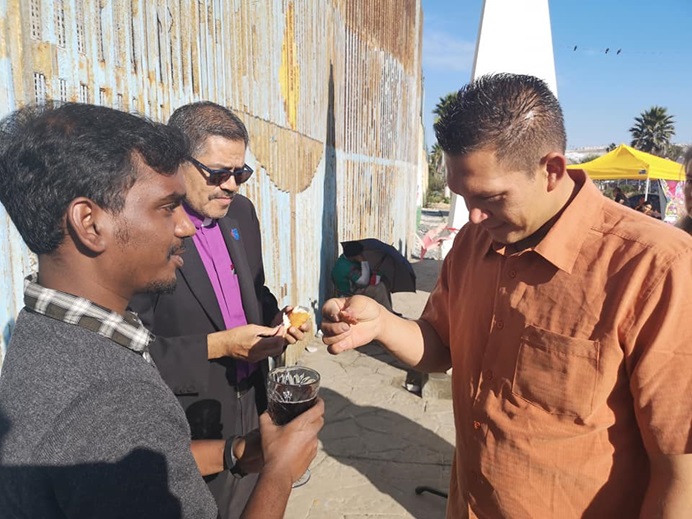 Bishop Felipe Ruiz-Aguilar (center) and United Methodist Global Ministries missionary Yabes Manokaran (left) share communion with migrants during a worship service at El Faro: The Border Church. Photo by Misael Ruiz Lara, Methodist Church of Mexico.