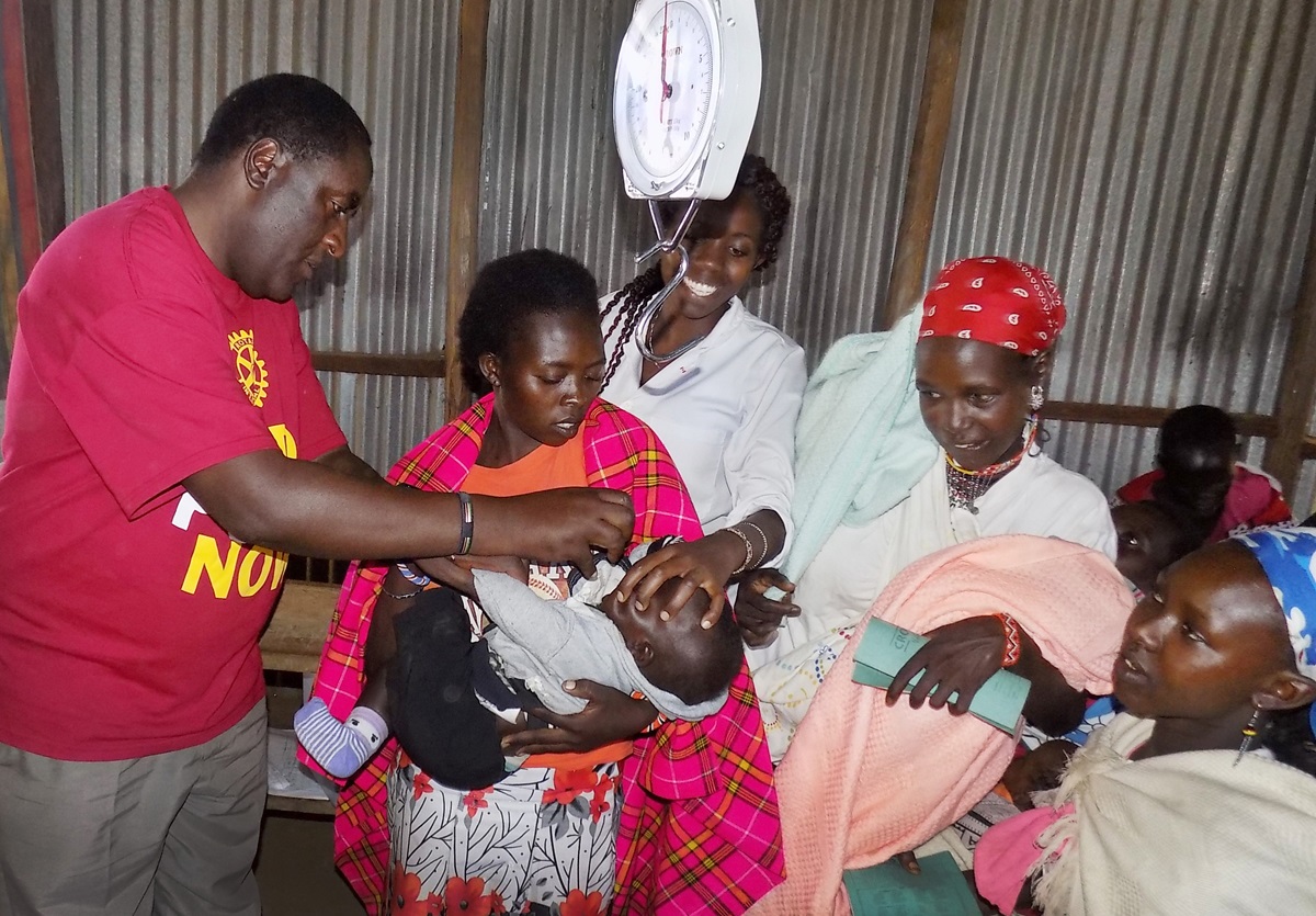 The Rev. Joe Kariuki Kamau, Narok District superintendent, assists nurses in giving a child a polio vaccine at Trinity Mobile Clinic in Gilgil, Kenya. Kamau uses the medical outreach to share the Gospel. Photo by Faith Wanjiru. 