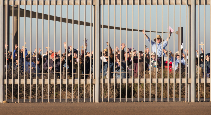 United Methodist pastor John Fanestil (standing above crowd at right) leads participants in a Posada celebration on the U.S. side of a secondary border fence that separates San Diego from Tijuana, Mexico. On the 25th anniversary of La Posada Without Borders, Friendship Park was closed on the U.S. side while hundreds gathered freely on the Mexico side. 