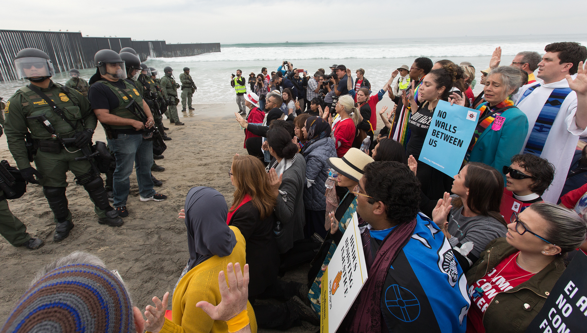 Faith leaders and other supporters of immigrant rights face U.S. Border Patrol agents at the fence between the U.S. and Mexico in San Diego. At bottom right is Emma Escobar of The United Methodist Church's Baltimore-Washington Conference. Photo by Mike DuBose, UMNS.