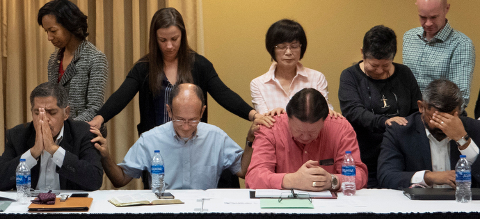 Members of the United Methodist Immigration Task Force pray with three bishops of the Methodist Church in Mexico at the beginning of the Jan. 21-23 meeting in McAllen, Texas. Mexico bishops, seated, from right, Felipe de Jesús Ruiz Aguilar, José Antonio Garza Castro (in red shirt) and Rodolfo Rivera de la Rosa (far left). Photo by Kathy L. Gilbert, UMNS.