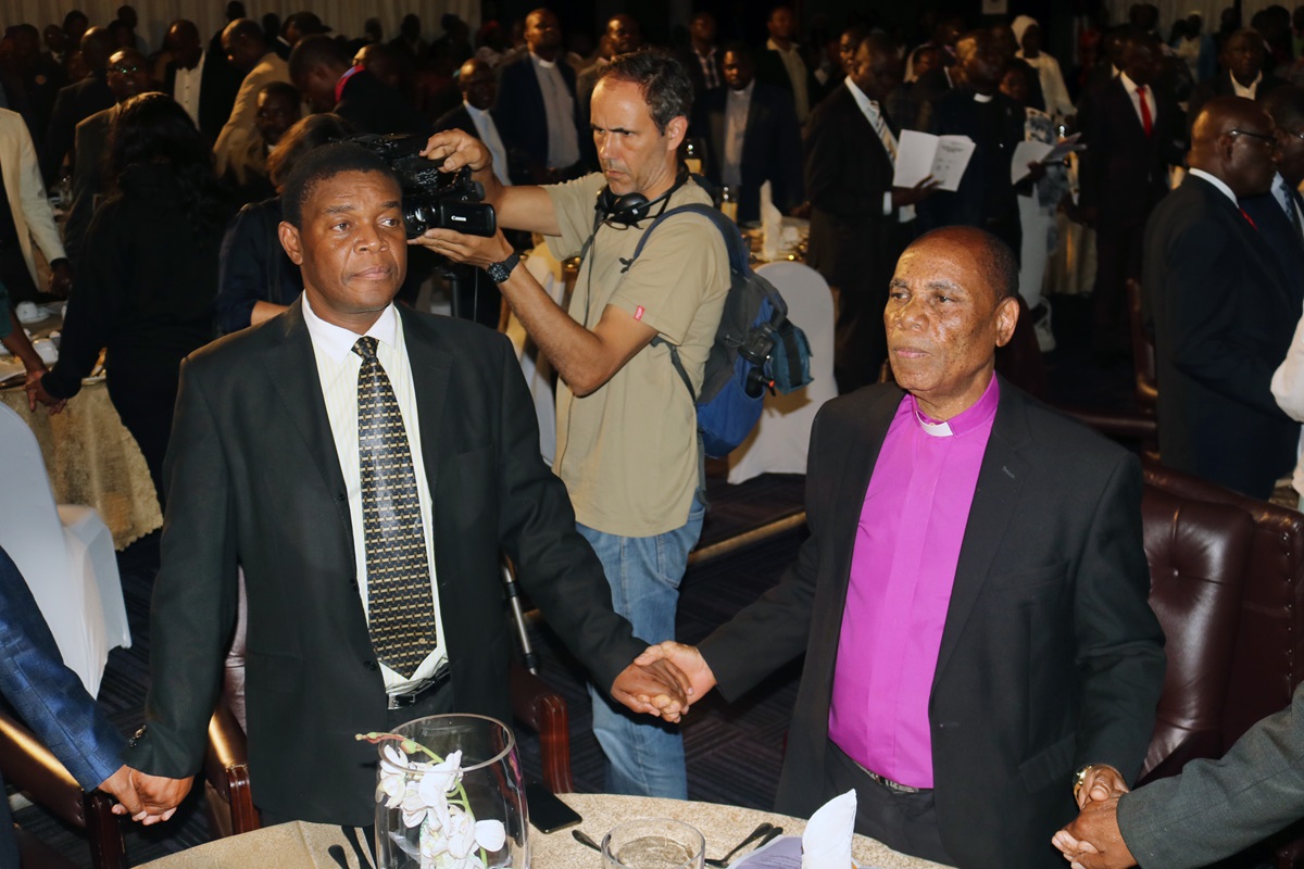 Zimbabwe Area Bishop Eben K. Nhiwatiwa, episcopal leader for the Zimbabwe East and Zimbabwe West conferences, joins hands with other Christians and political leaders at a national prayer breakfast and dialogue Feb. 7 in Harare, Zimbabwe. Photo by Tarui Emmanuel Maforo, UMNS. 