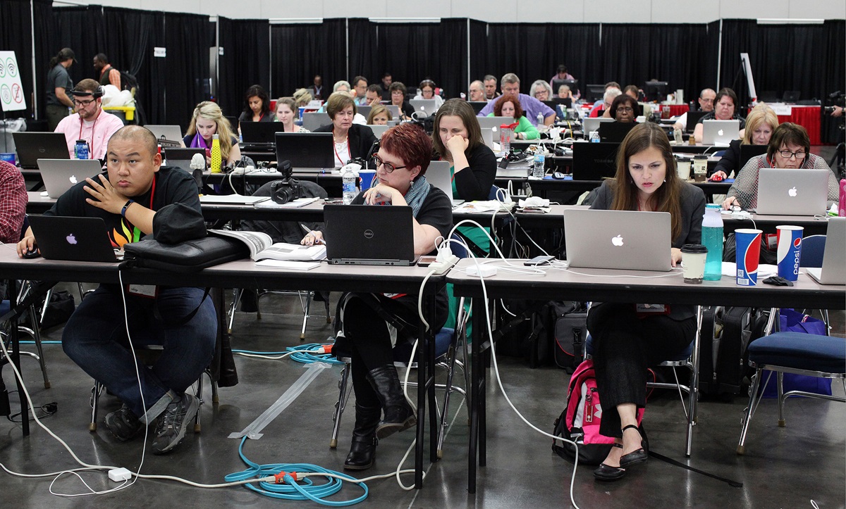 A General Conference newsroom is a busy place, hosting United Methodist News reporters, conference communicators, secular publication reporters and others. Kathy L. Gilbert (center) was among those filing stories from the newsroom at the 2016 General Conference in Portland, Oregon. Photo by Kathleen Barry, UMNS.