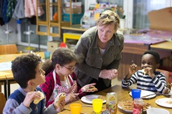 Volunteer Hannah Guzinski helps serve a meal to immigrant children in an educational enrichment program at the United Methodist Peace Church in Hamburg, Germany. Photo by Mike DuBose, UMNS.