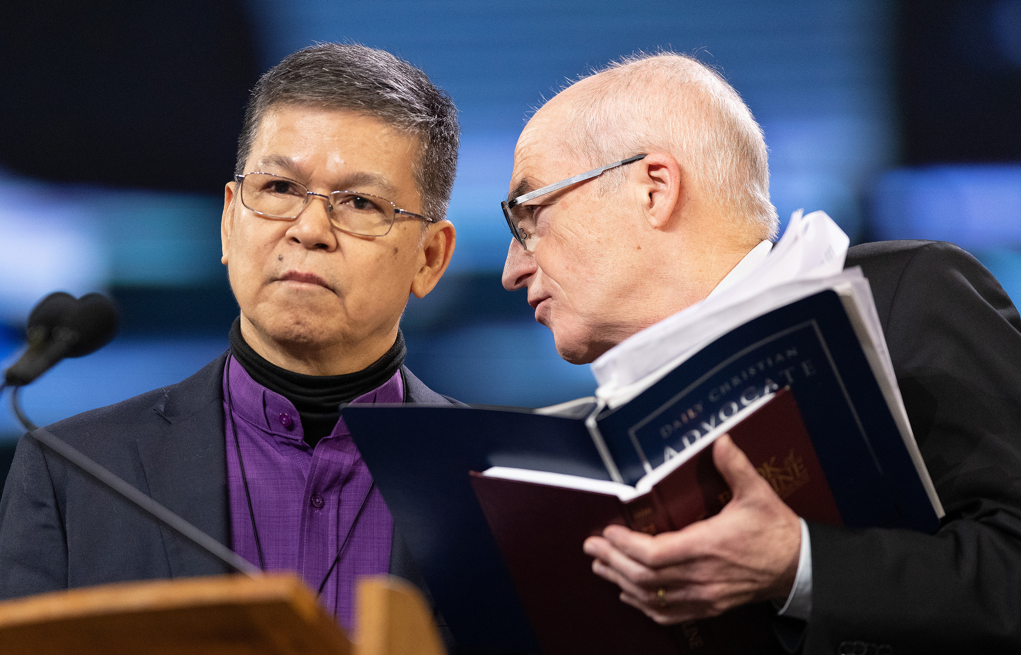 Os Bispos Ciriaco Q. Francisco (à esquerda) e Patrick Streiff conferenciam-se no pódio durante a Conferência Geral da Metodista Unida de 2019 em St. Louis. Ambos servem na Comissão Permanente para os Assuntos das Conferências Centrais. Foto de Mike DuBose, UMNS.